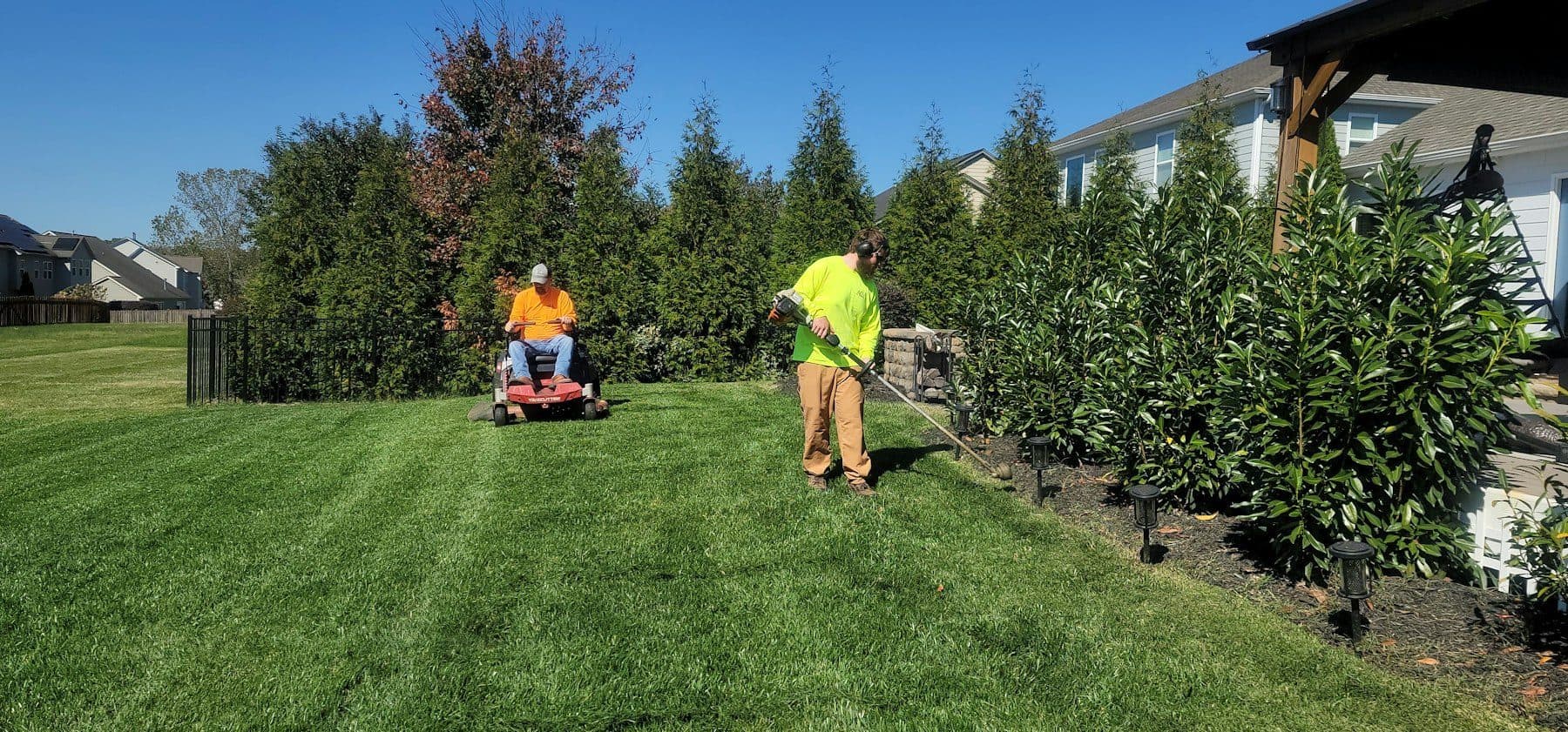 Landscaping crew mowing and trimming a green lawn