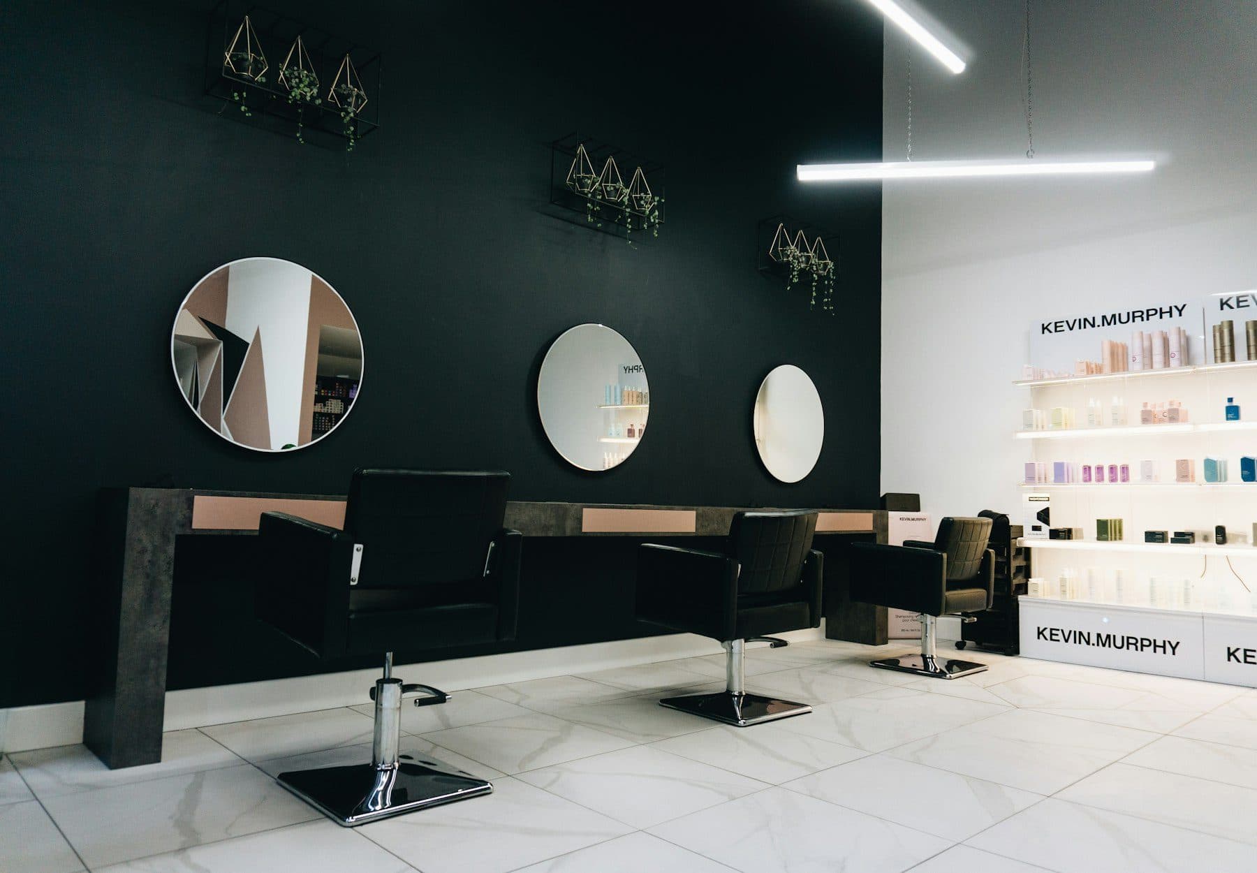 Minimal hair salon with round mirrors and black chairs